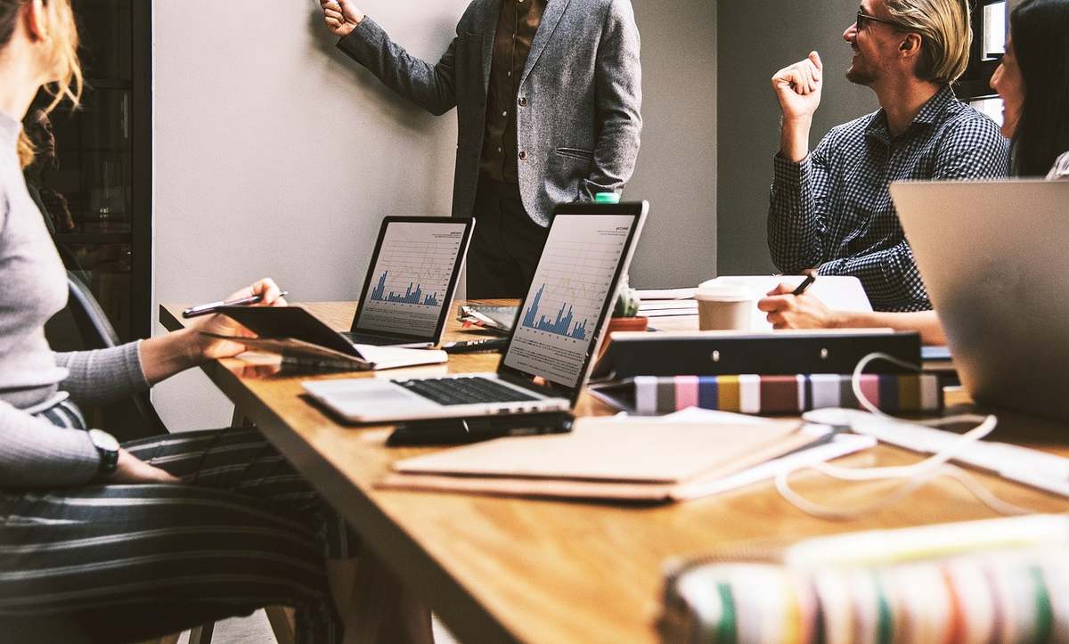 Équipe réunie autour d'une table de travail avec ordinateurs portables et documents professionnels