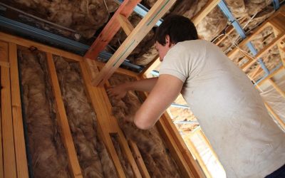 Un homme installe de l'isolation dans un plafond
