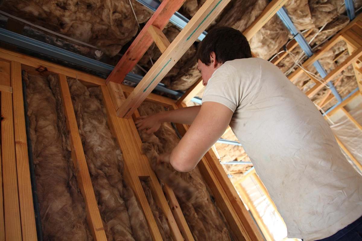 Un homme installe de l'isolation dans un plafond