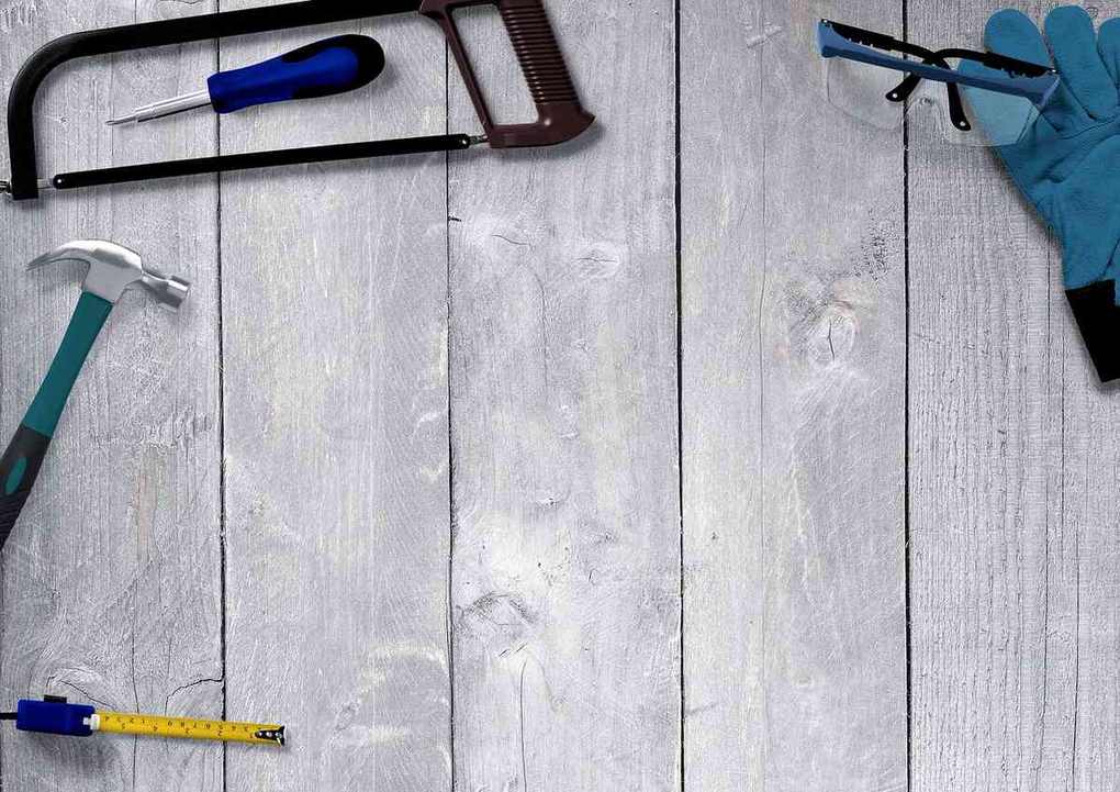 Tournevis, marteau, scie et autres outils disposés sur un plan de travail en bois clair Tournevis, marteau, scie et autres outils disposés sur un plan de travail en bois clair
