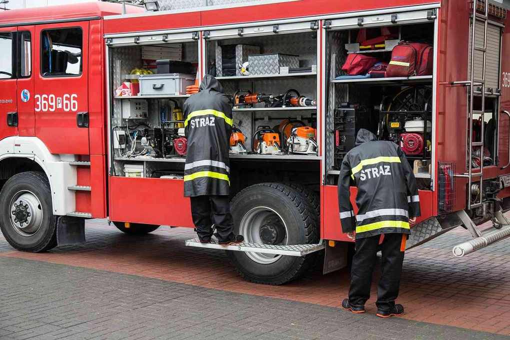 Pompiers vérifient l'équipement dans le compartiment arrière d'un camion de pompiers rouge